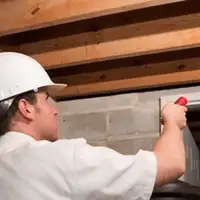 Termite inspection technician checking a basement wall and framing for termite activity in Chicago, IL